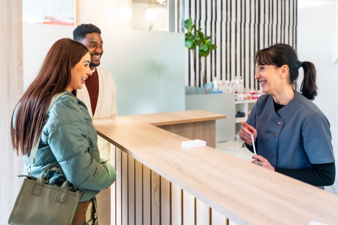 A clinic receptionist greeting a patient at the front desk