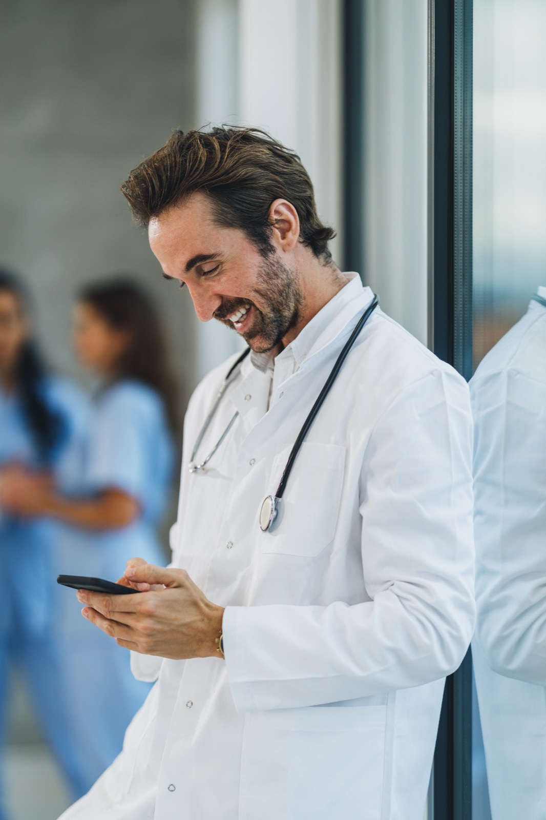 A smiling doctor reading a message on their phone