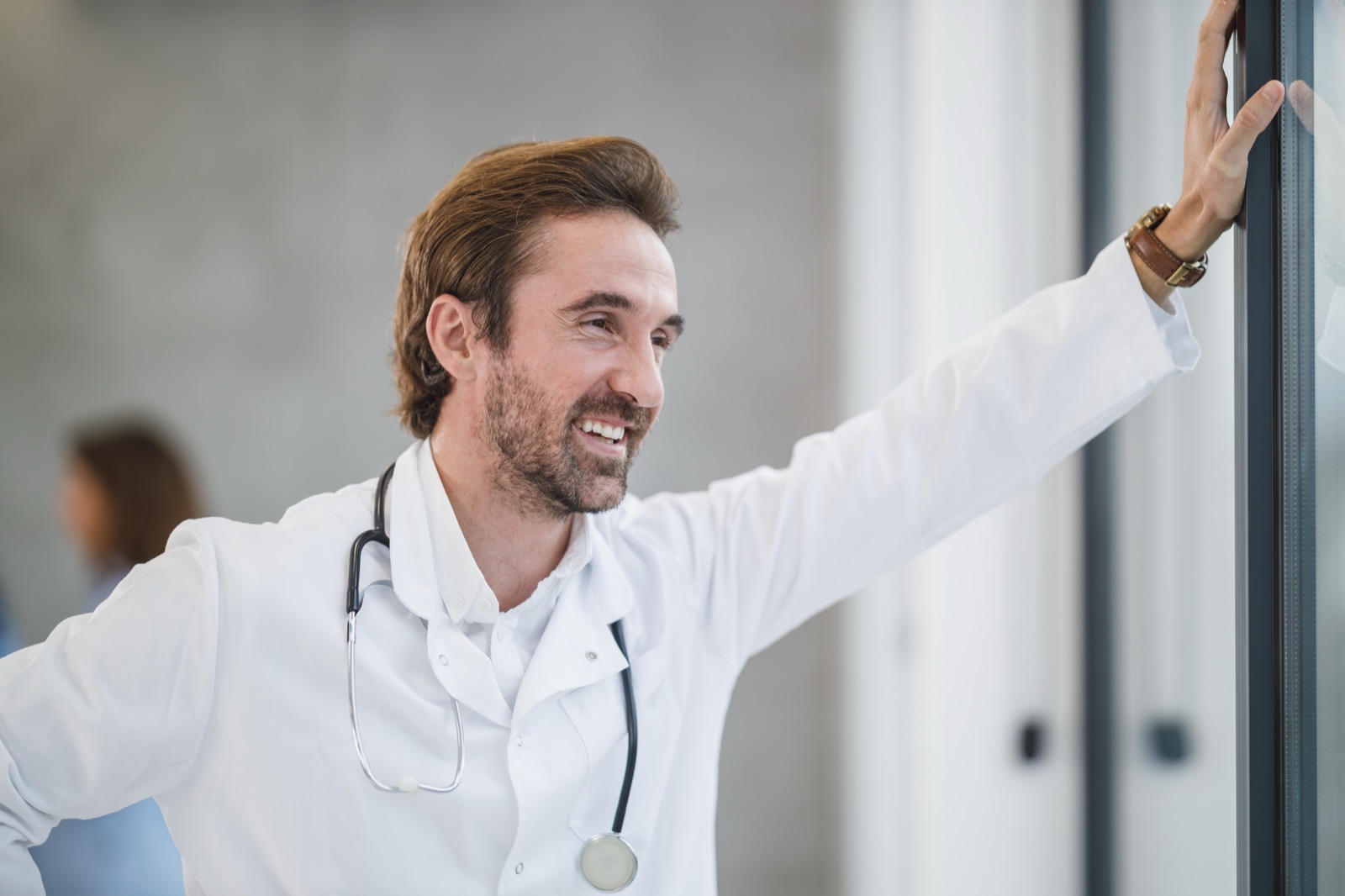 A smiling doctor leaning on a clinic window